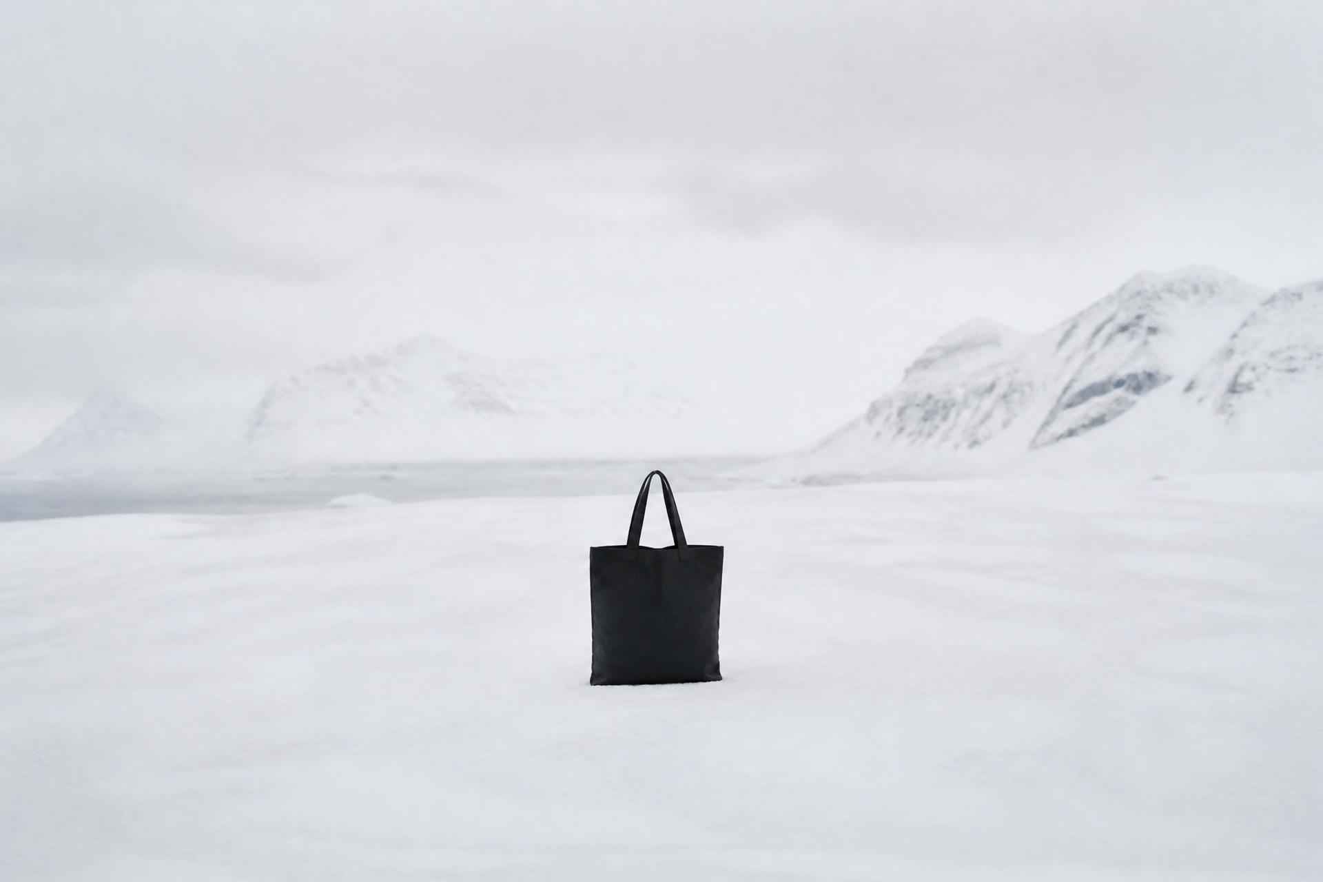 Black canvas tote standing upright in deep snow in an empty Arctic landscape